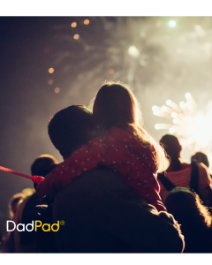 Dad and daughter watching a fireworks display together, daughter holding on tightly to her dad.